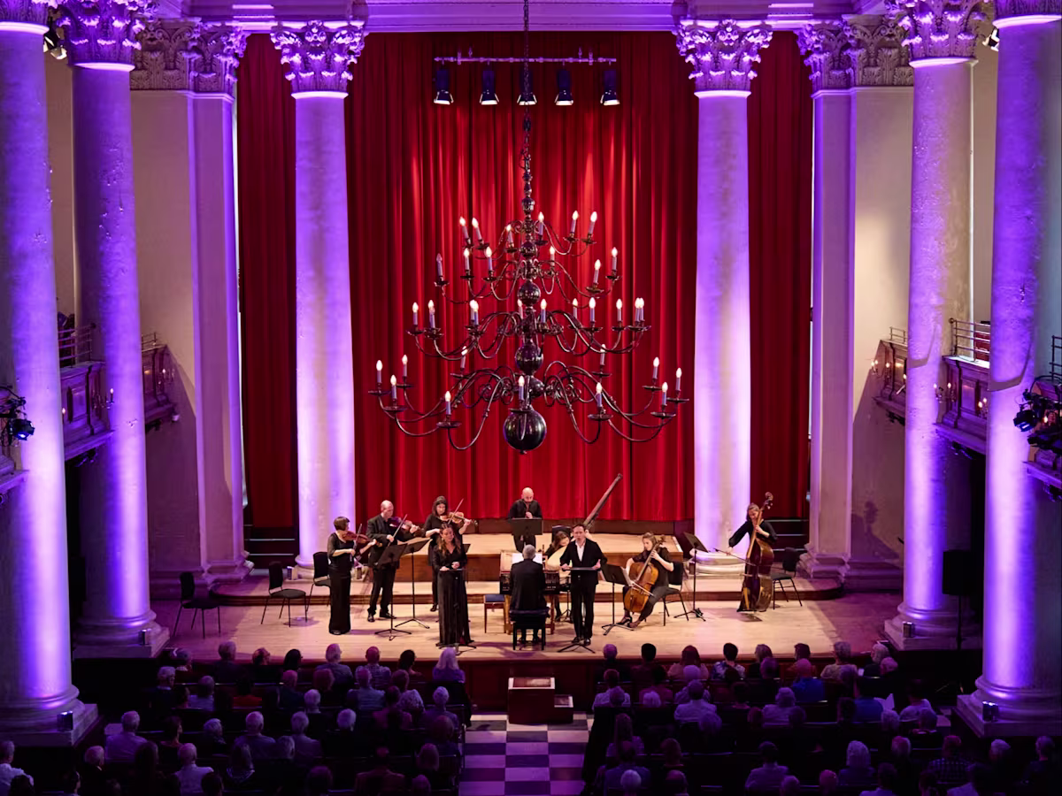 London Festival of Baroque Music Musicians performing on stage of Smith Square Hall in London with purple atmospheric lighting framing the pillars behind the stage