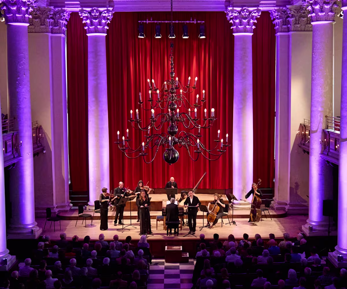 London Festival of Baroque Music Musicians performing on stage of Smith Square Hall in London with purple atmospheric lighting framing the pillars behind the stage
