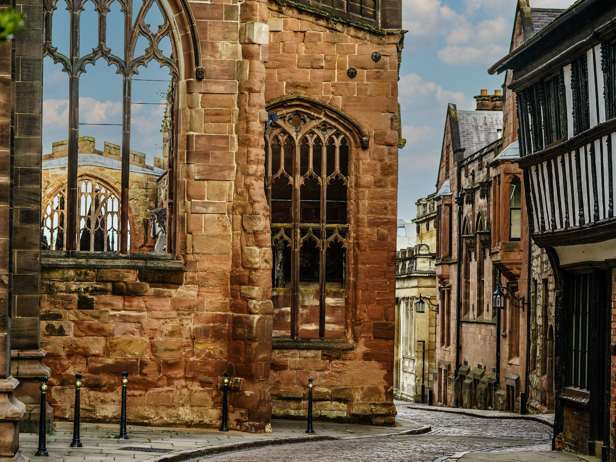 a cobbled street twists past the ruins of coventry cathedral