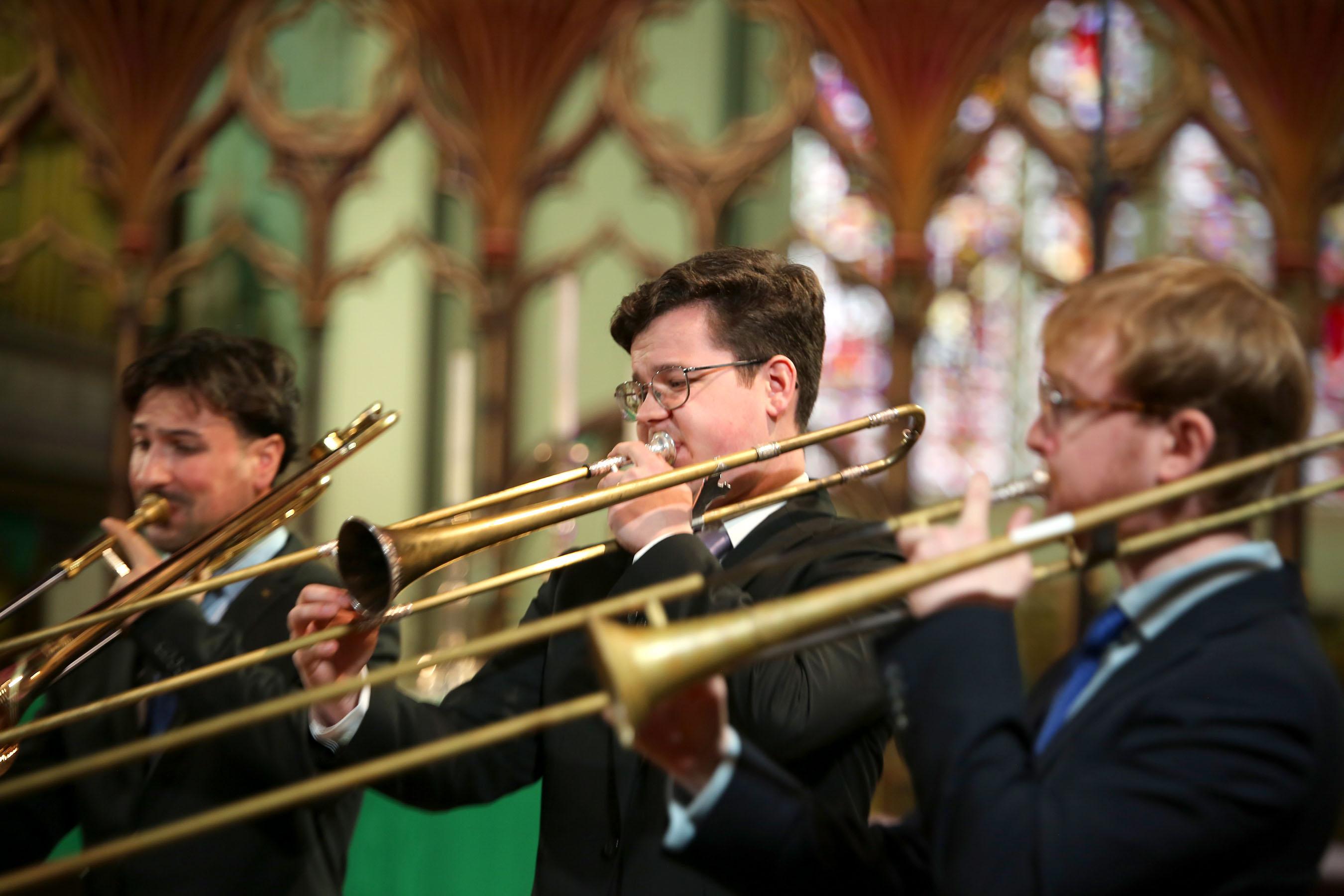 three baroque sackbut players blowing down their instruments
