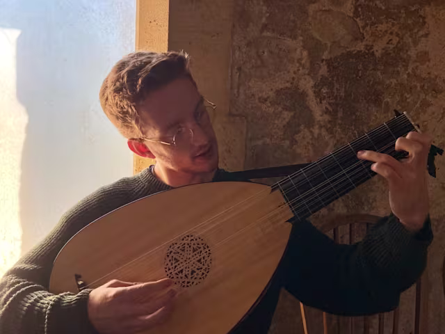 The Last Lute Player a man playing a lute sat on a stone windowsill