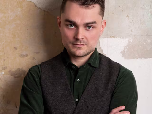 Rossini: Sacred & Profane Jakob Lehmann standing arms folded against a wall with peeling wallpaper