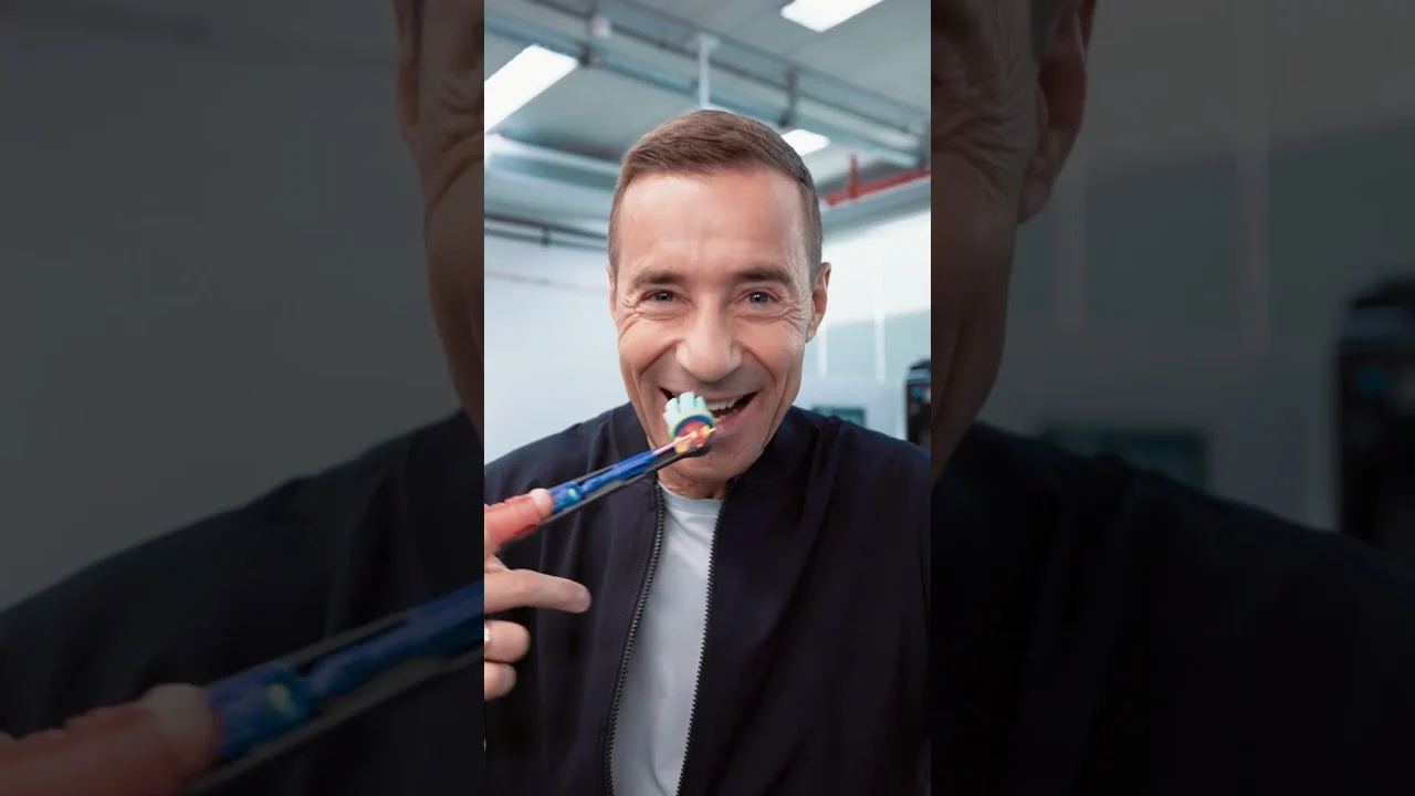 Mann hält eine Oral-B-Zahnbürste bei einer Vorführung.