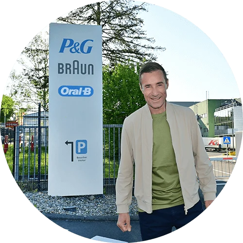 Kai Pflaume, P&G Markenbotschafter der Kampagne 'Wo Qualität zu Hause ist', steht vor dem Eingang eines P&G Werks.
