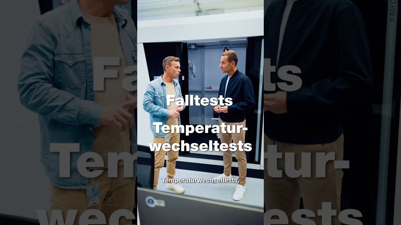 Zwei Personen im Gespräch neben einer Testkammer.