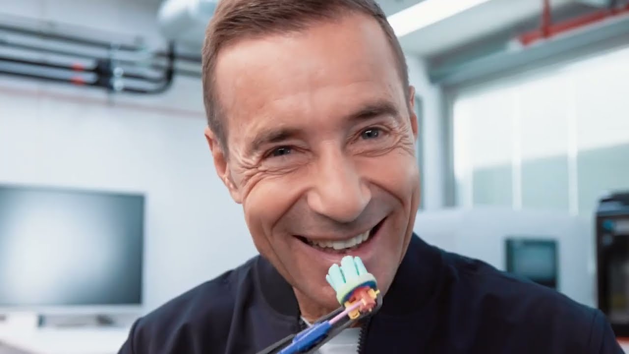 Nahaufnahme einer Person, die eine Zahnbürste vor die Zähne hält, in einer Laborumgebung mit sichtbaren Geräten im Hintergrund.
