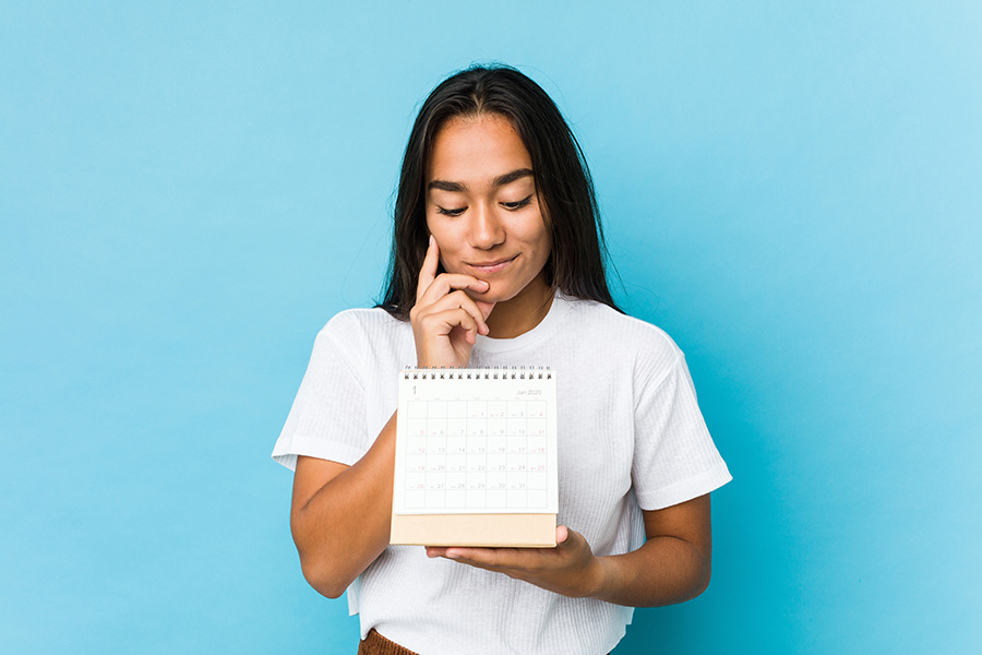 Une femme marque les jours au stylo rouge sur un calendrier