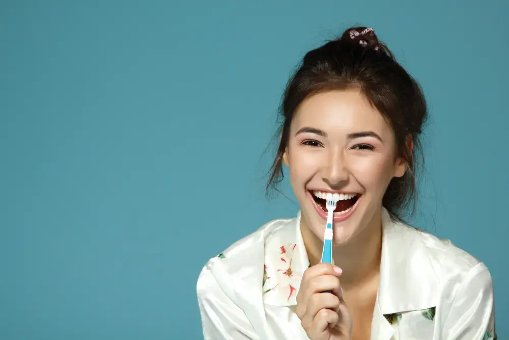 Eine Frau, die lächelt und die eine Zahnbürste im Mund hat