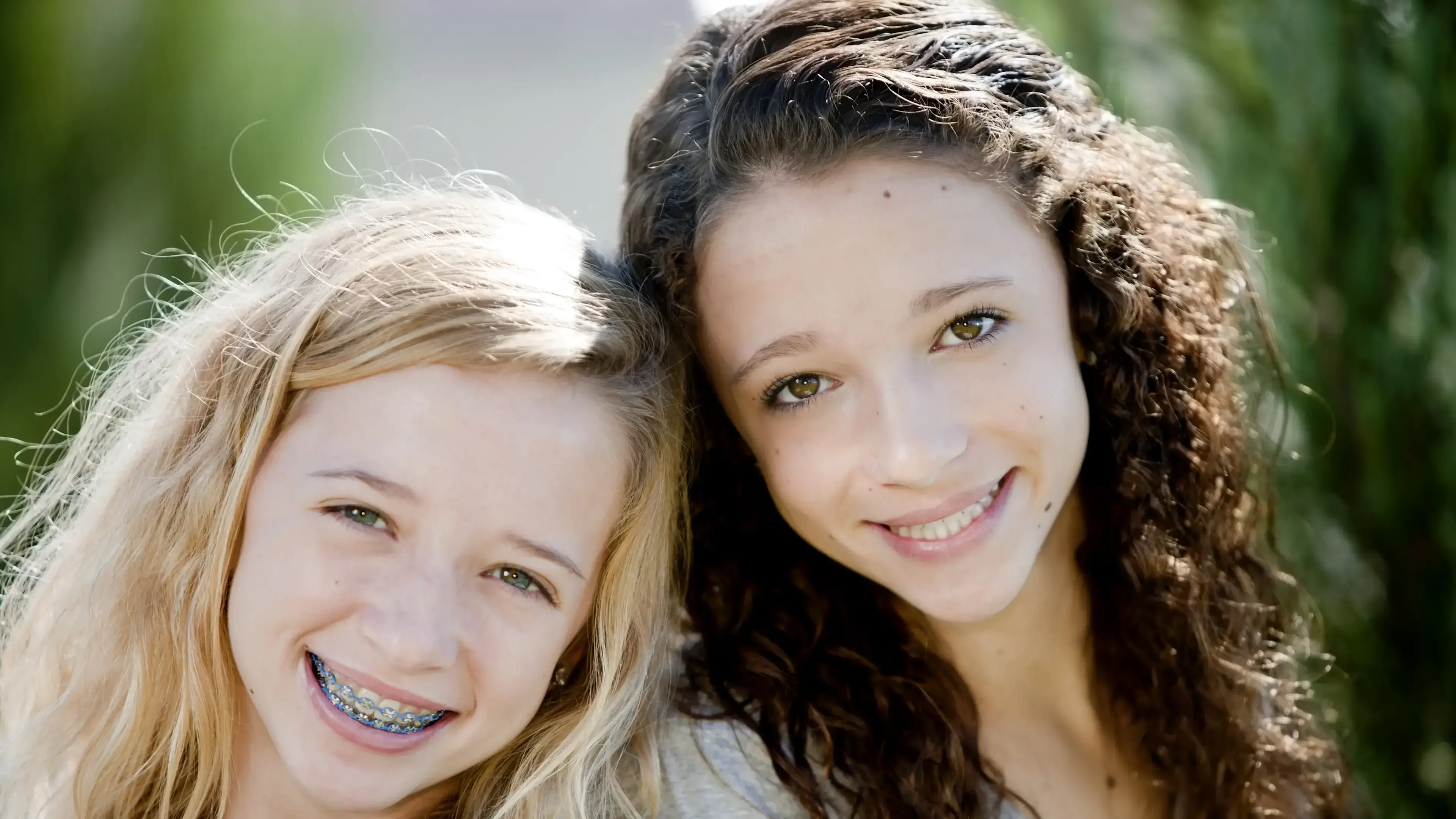 Zwei Mädchen mit Zahnspangen, die in die Kamera lächeln.