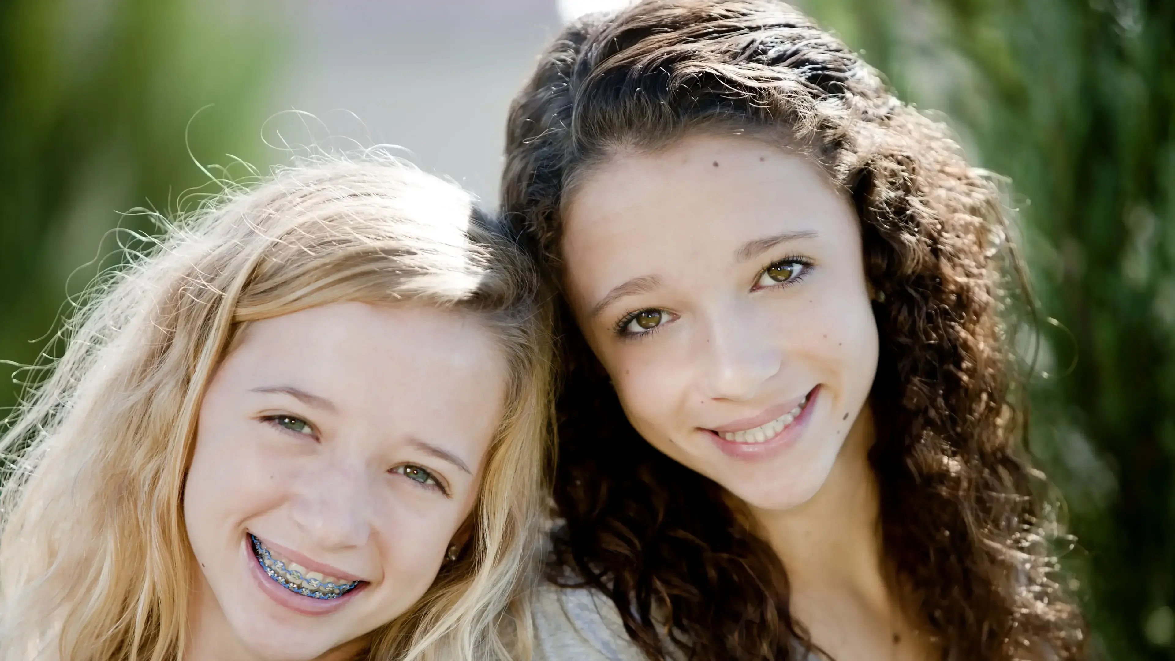 Zwei Mädchen mit Zahnspangen, die in die Kamera lächeln.