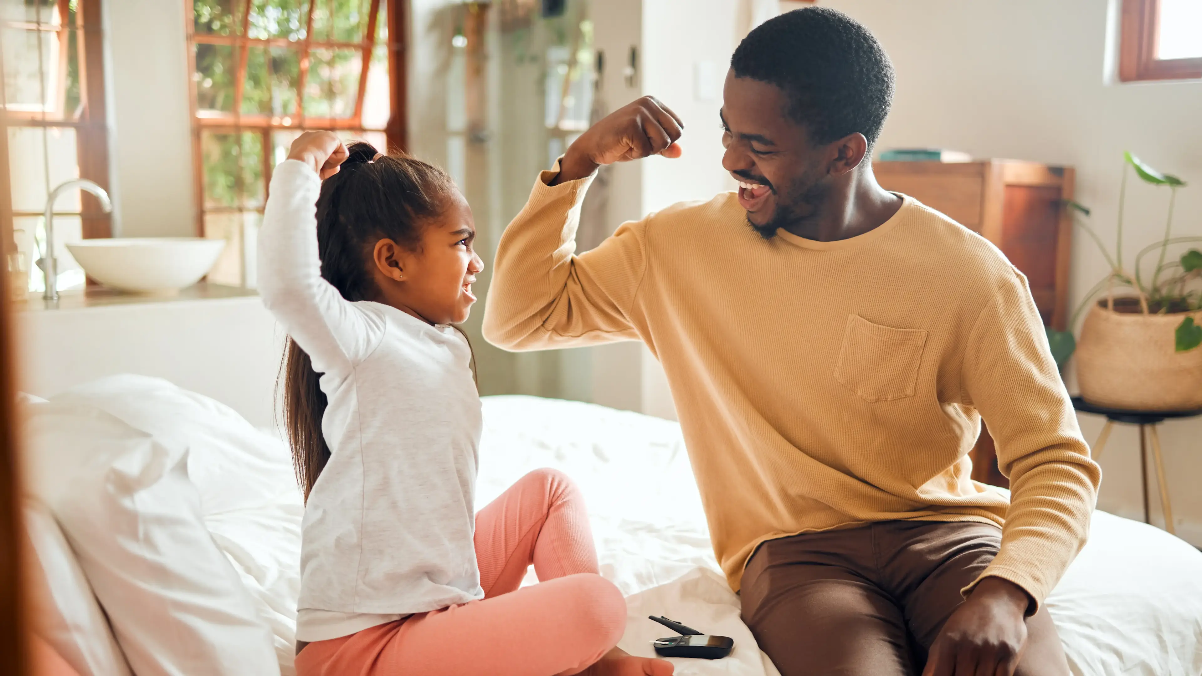 Ein Mann und ein Kind machen reißen spielerisch die arme zu einer Kraftpose hoch.
