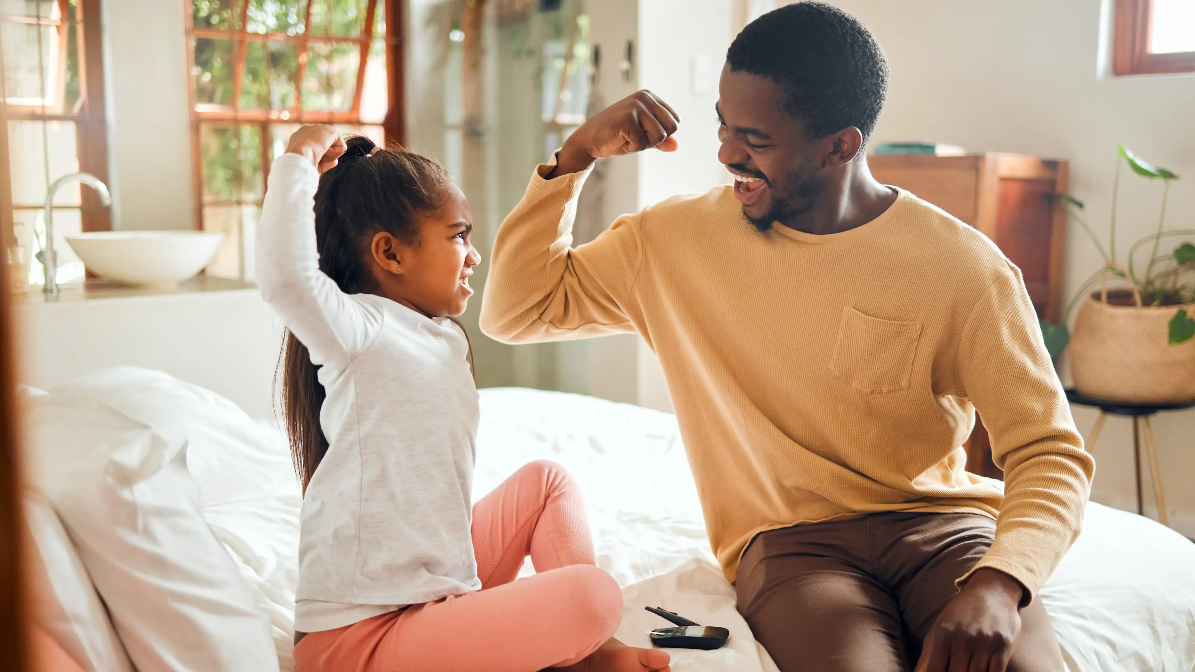 Ein Mann und ein Kind machen reißen spielerisch die arme zu einer Kraftpose hoch.