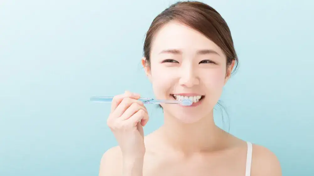 Eine asiatische jüngere Frau, die sich die Zähne putzt.