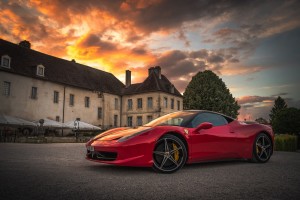 Photo of a Ferrari in front of a mansion at sunset