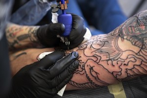 Image of a tattoo artist laying down a tattoo