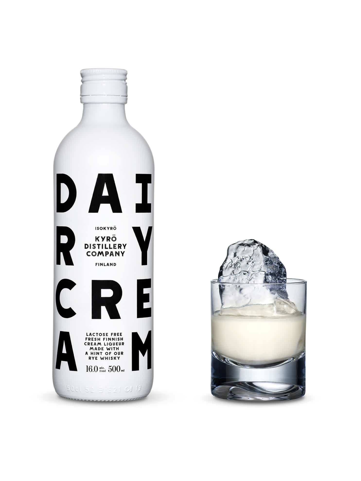 White, opaque bottles of Dairy Cream liquor with black font and Kyrö logo next to a tumbler glass filled with a shard of hand-cut ice and Dairy Cream liquor. Produced in Isokyrö, Finnland. 