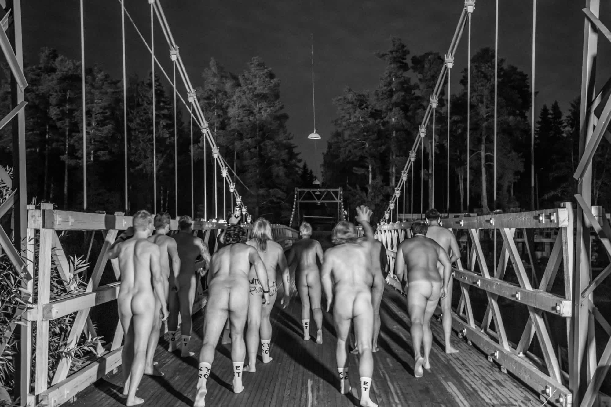 A bunch of naked people on a bridge in the middle of the night. 