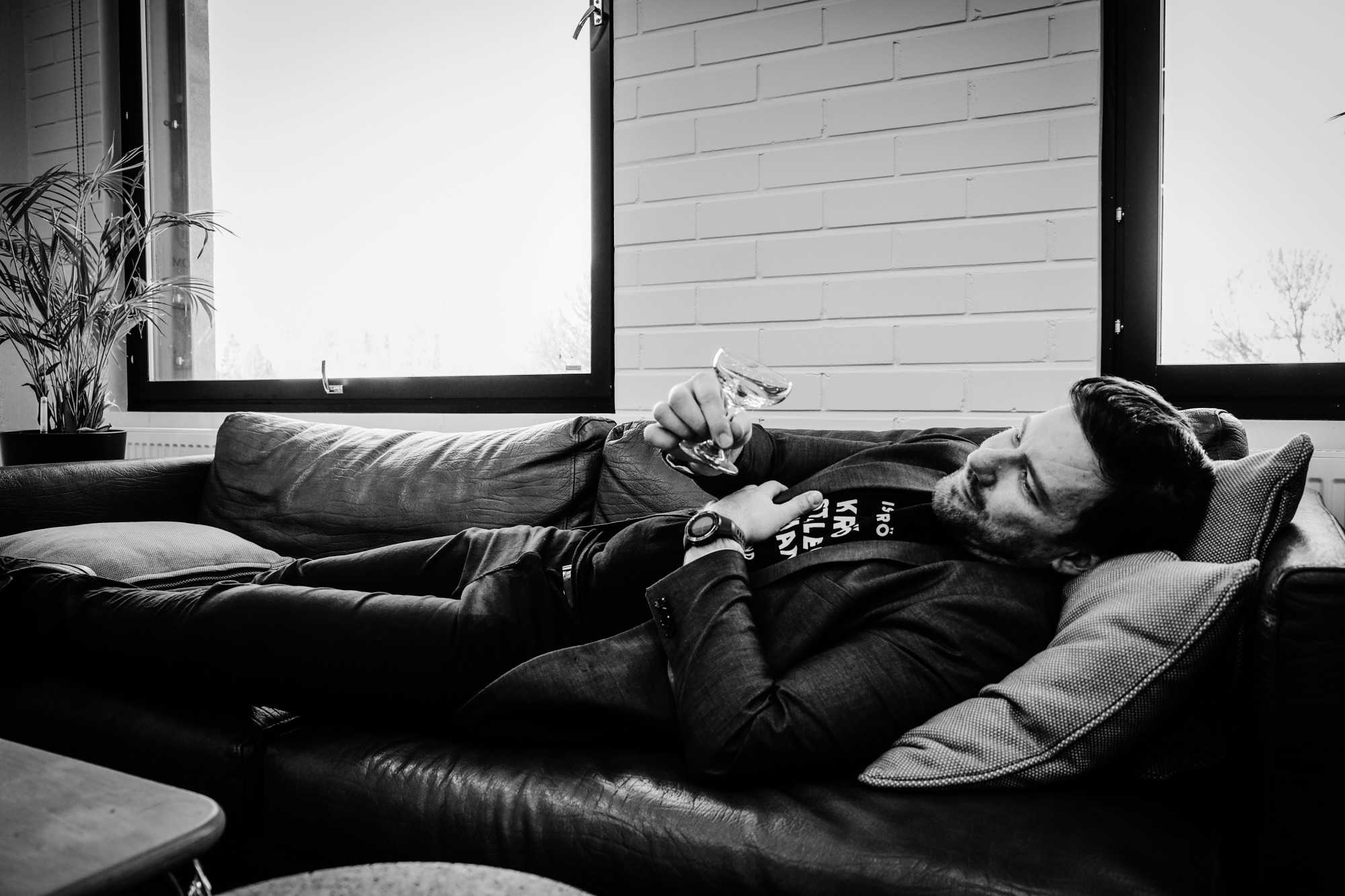 Man laying on a couch looking at an empty glass and dreaming of a cocktail.