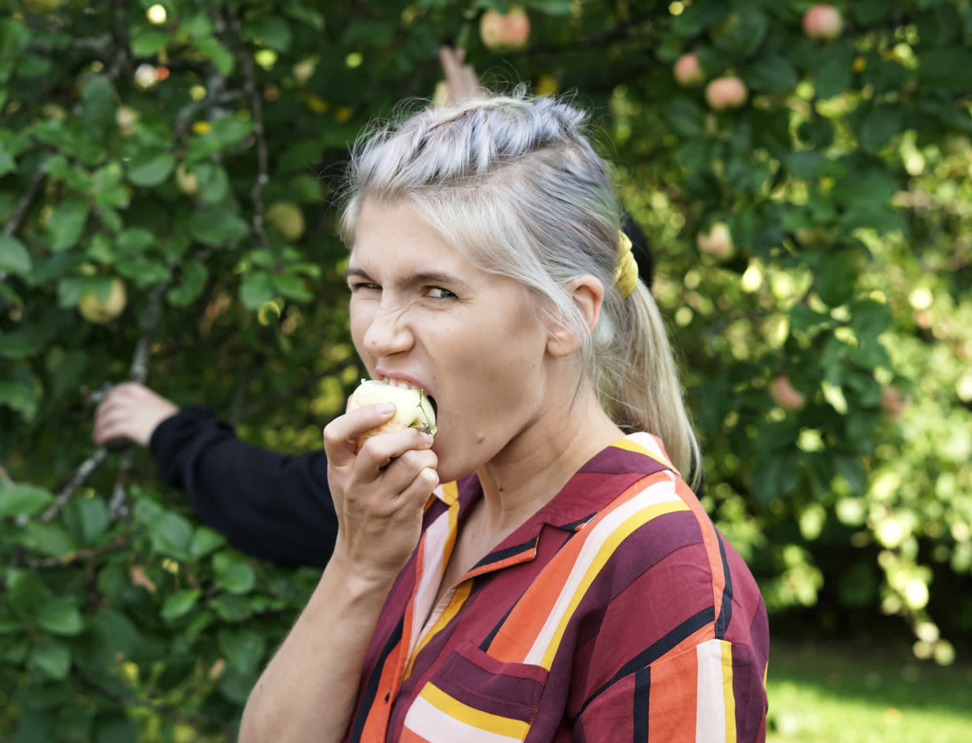 A young woman biting into an apple.
