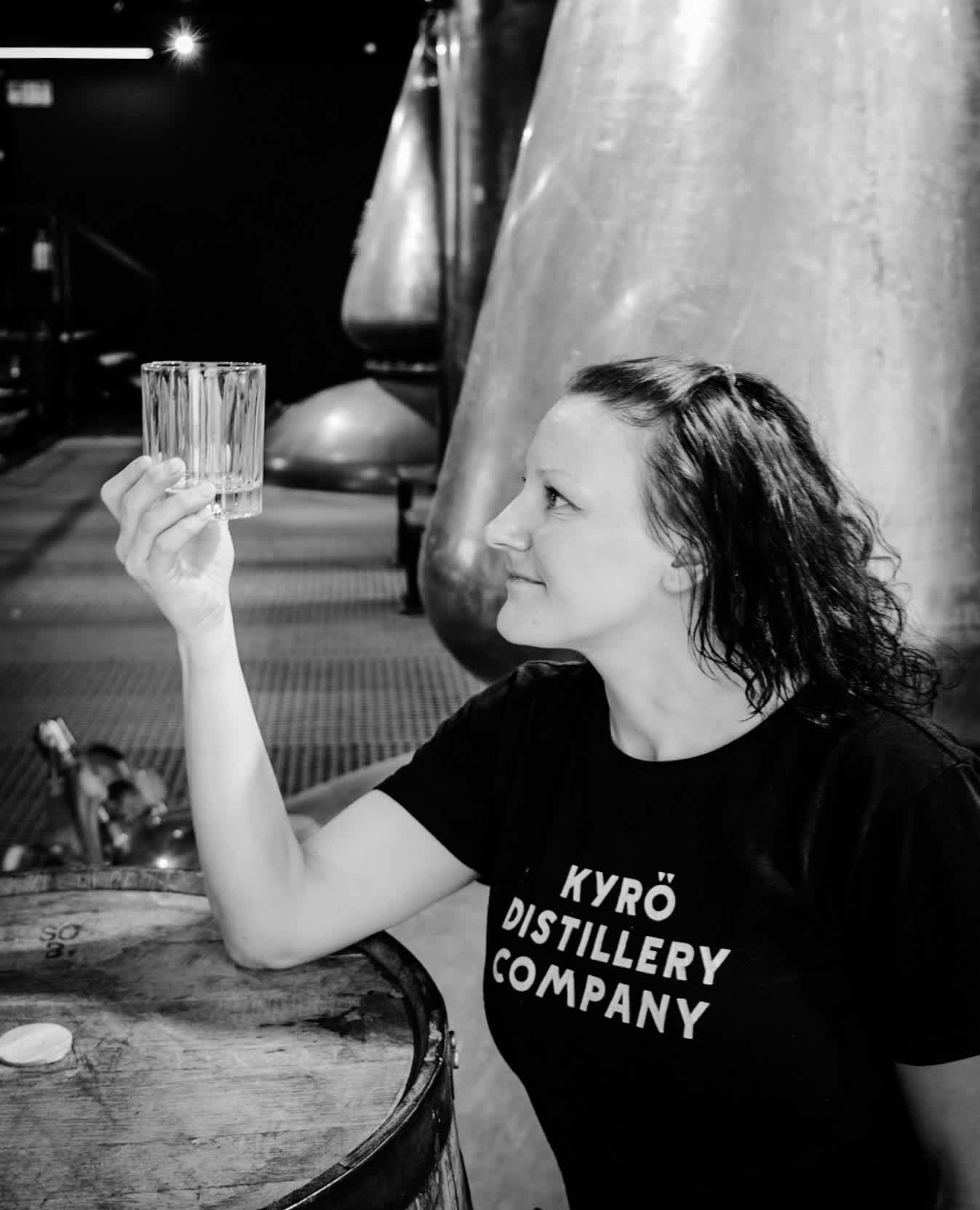 Woman looking at an empty glass in a distillery.