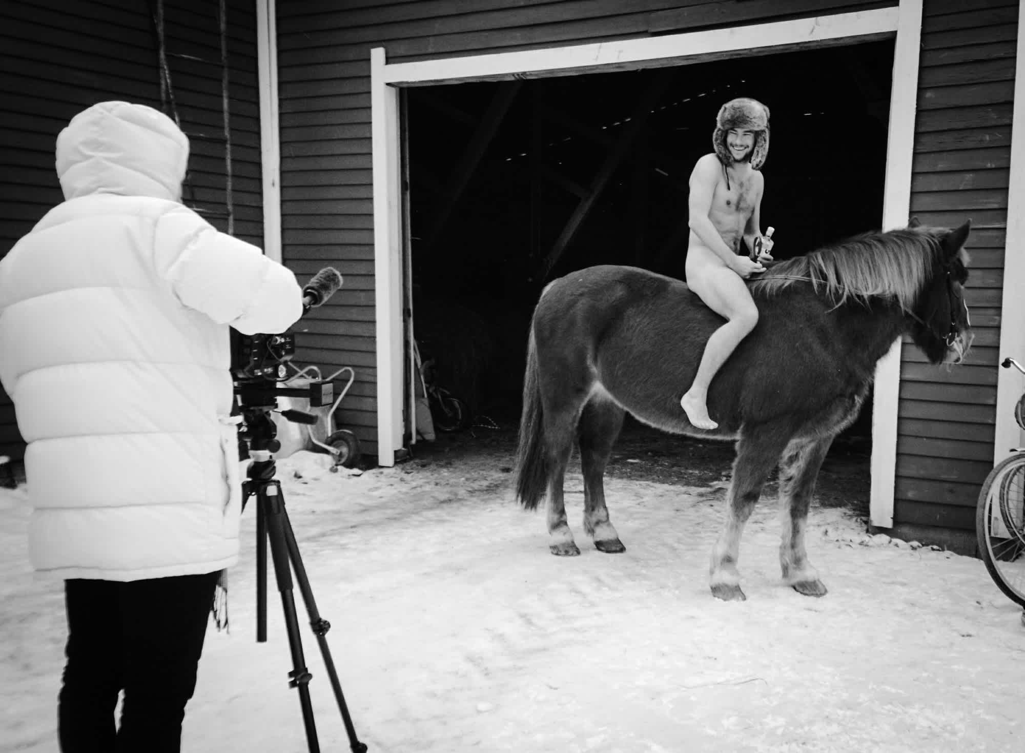 Naked man on a horse being photographed.