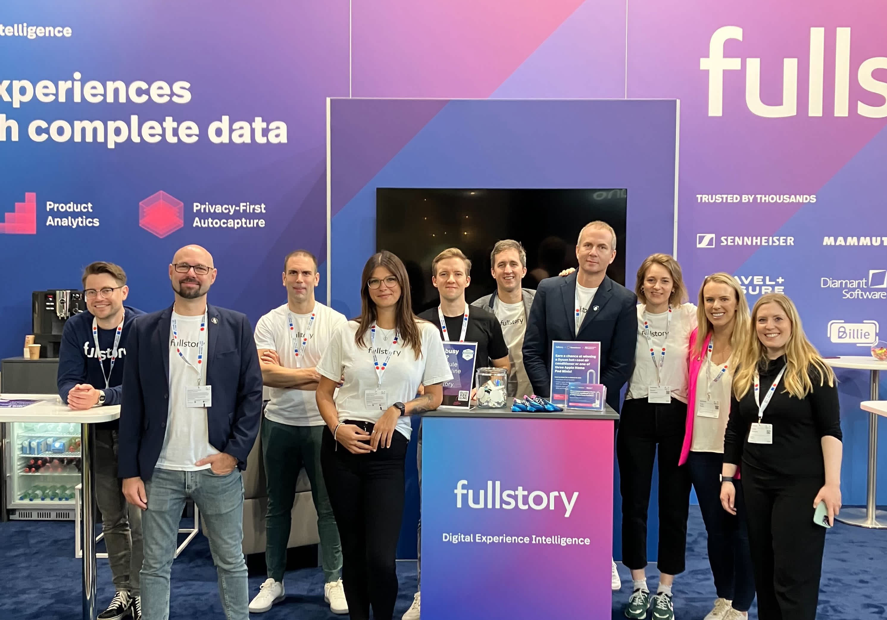 Team of nine FullStory employees, standing in a blue event booth at the DACH event in Germany