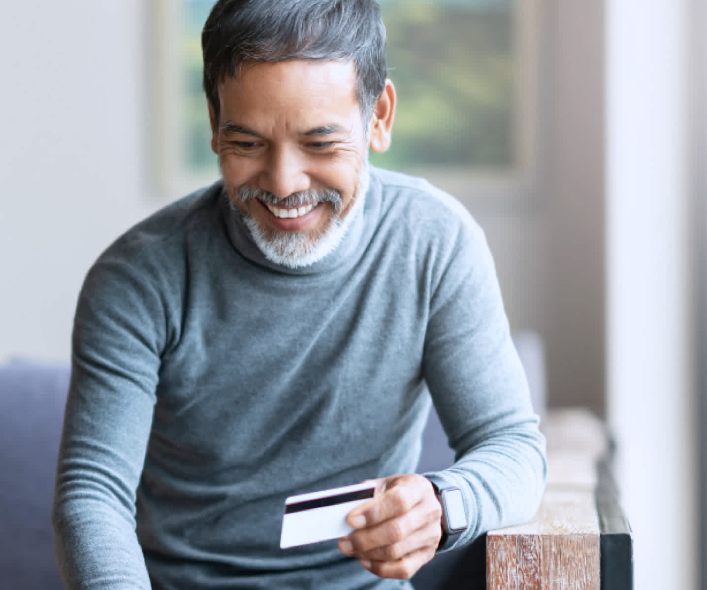 Man smiling while holding credit card