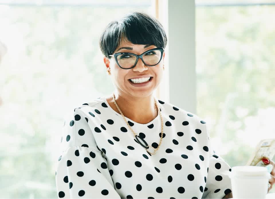 Woman with a polka dot shirt smiling in a meeting