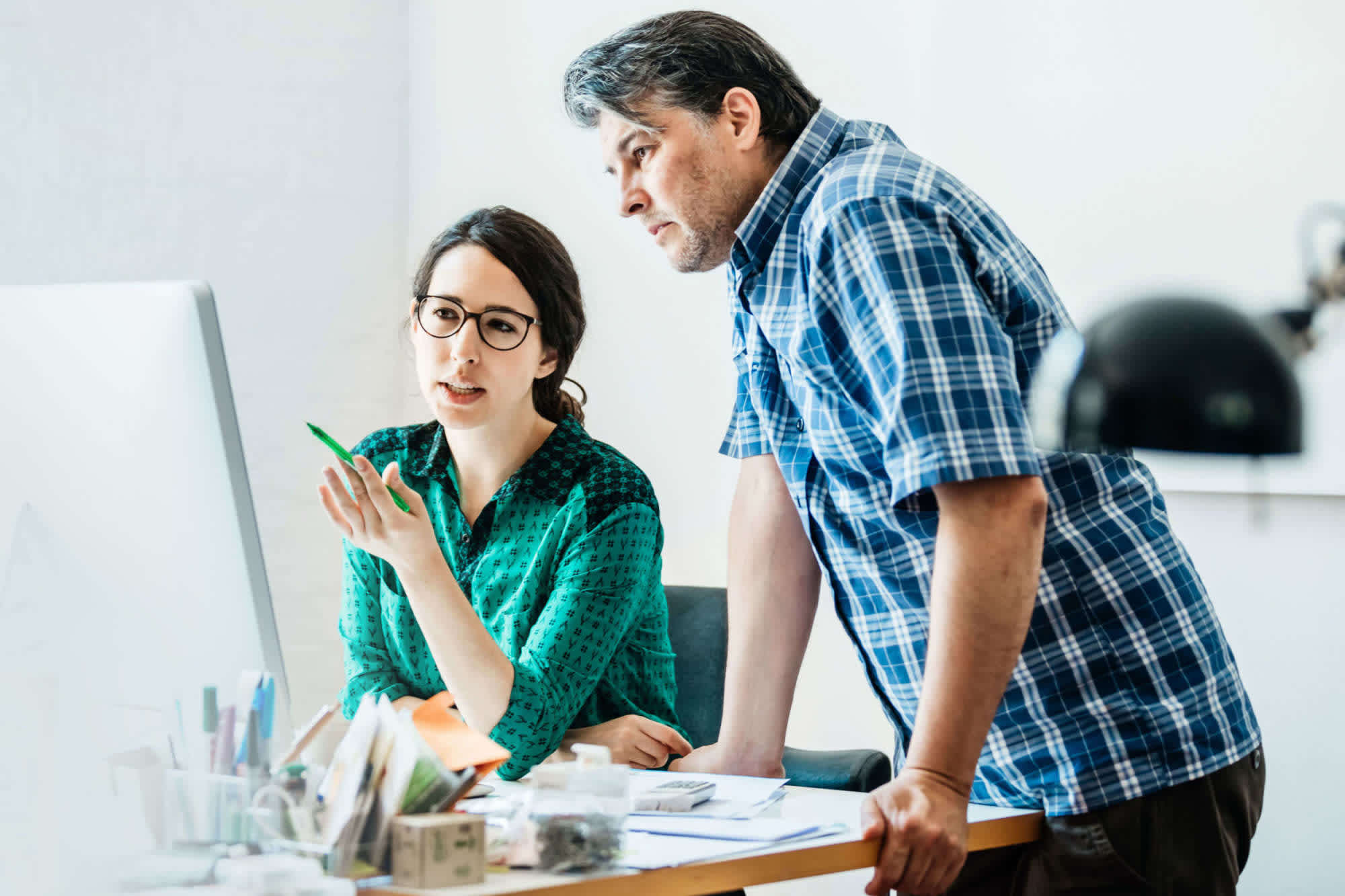 Two colleagues observing what's happening on a computer monitor