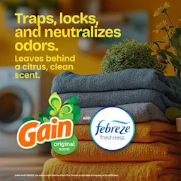 The words "Traps, locks and neutralizes odors. Leaves behind a citrus clean scent. Gain" and a febreze freshness logo over a laundry room with folded towels background