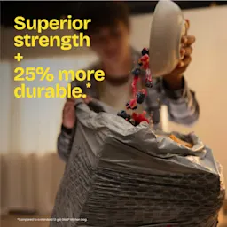 A person pouring berries into a trash bag from a white bowl