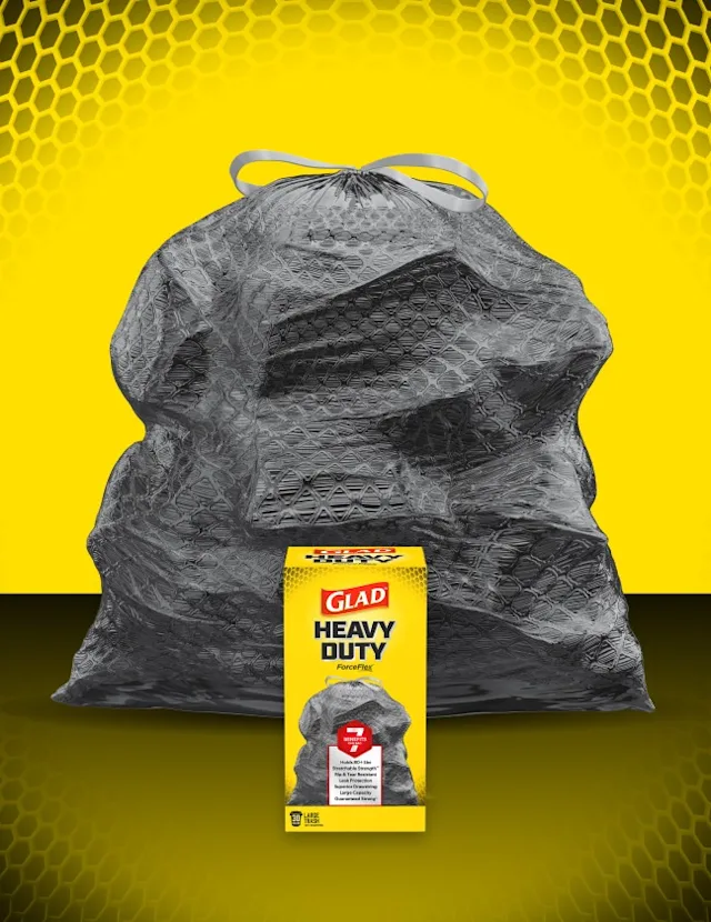 Black drawstring bag with yellow background with black circles, bottom of image is gradient yellow to black. Box of Glad trash bags sits in front of bag.