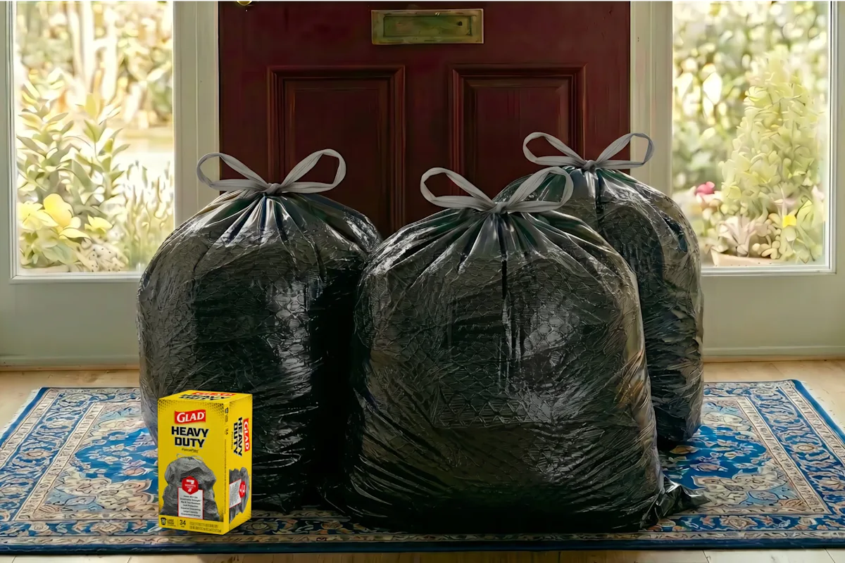 Three filled Glad ForceFlex trash bags by a front door, ready for donation pickup