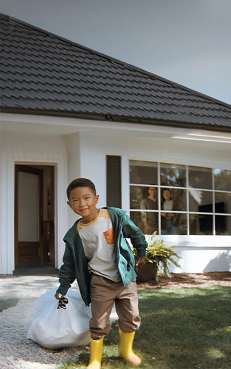 Boy dragging a trash bags in front of a house.