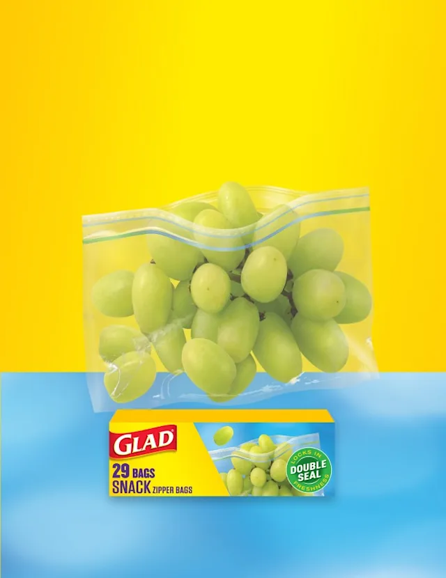 Bag of green grapes, box of Glad food bags, on a yellow and blue background.