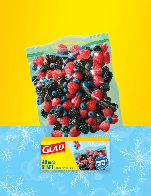 Food bag of strawberries and blueberries on a background of yellow. Bottom of image is light blue with snowflake illustrations. A box of Glad food bags is in front.