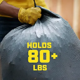 A hand holding a full black trash bag with the words "Holds 80+ lbs" in yellow