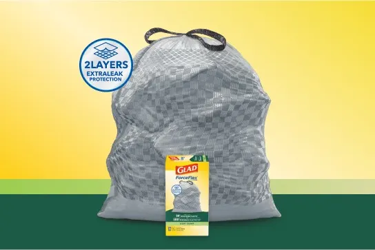 Gray trash bag with black handles on a yellow and green background with a badge that says "2 layers extra leak protection"
