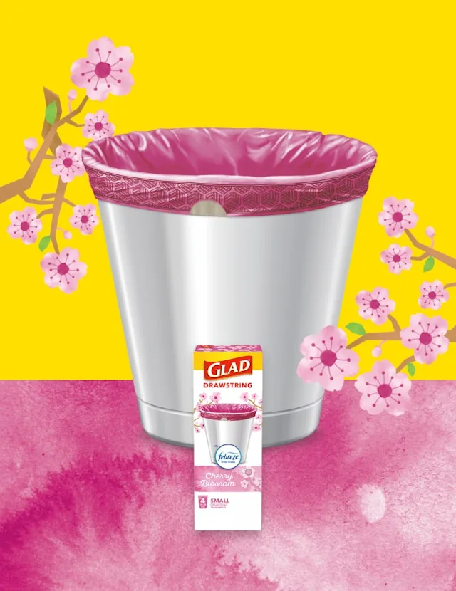 Glad drawstring trash bag in a silver trash can with cherry blossom design, set against a yellow background with cherry blossoms.