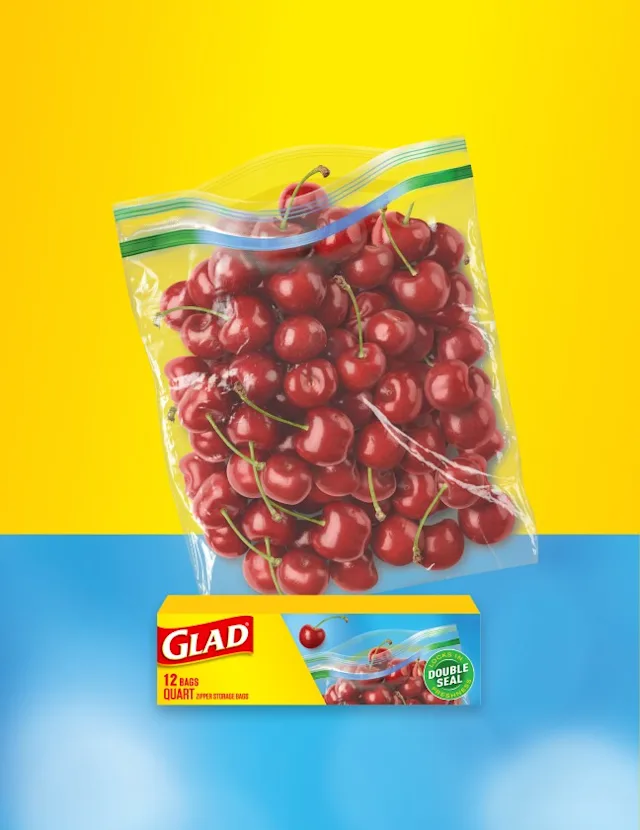 Food bag of cherries on a background of yellow and light blue. A box of Glad food bags is in front.