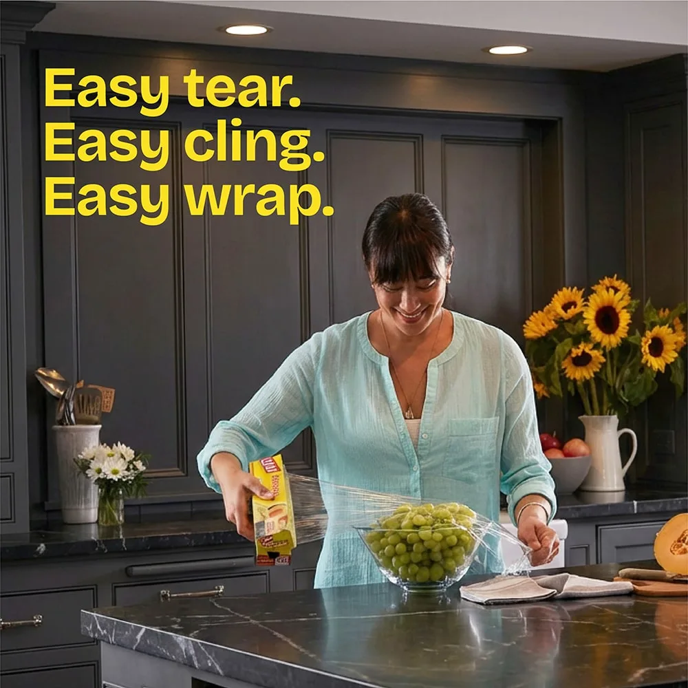 A woman coverin a bowl of grapes with Cling'n Seal in a kitchen. The words "Easy tear. Easy cling. Easy wrap."