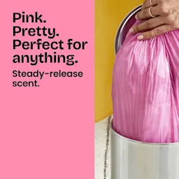 A person pulling a pink-colored trash bag out of a trash can. The words "Pink. Pretty. Perfect for anything" in black type of pink