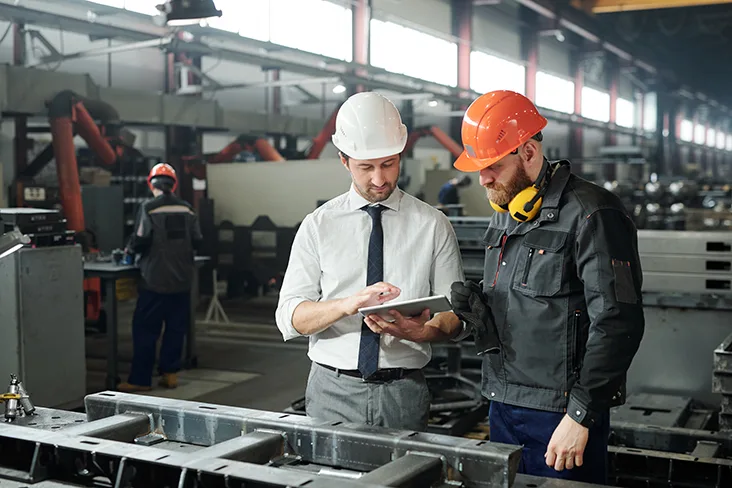 Two male construction workers looking at an iPad