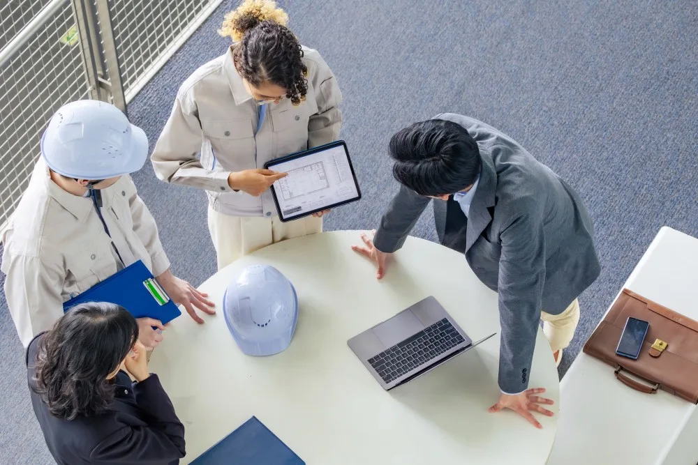 Over head shot of four employees standing looking at an iPad
