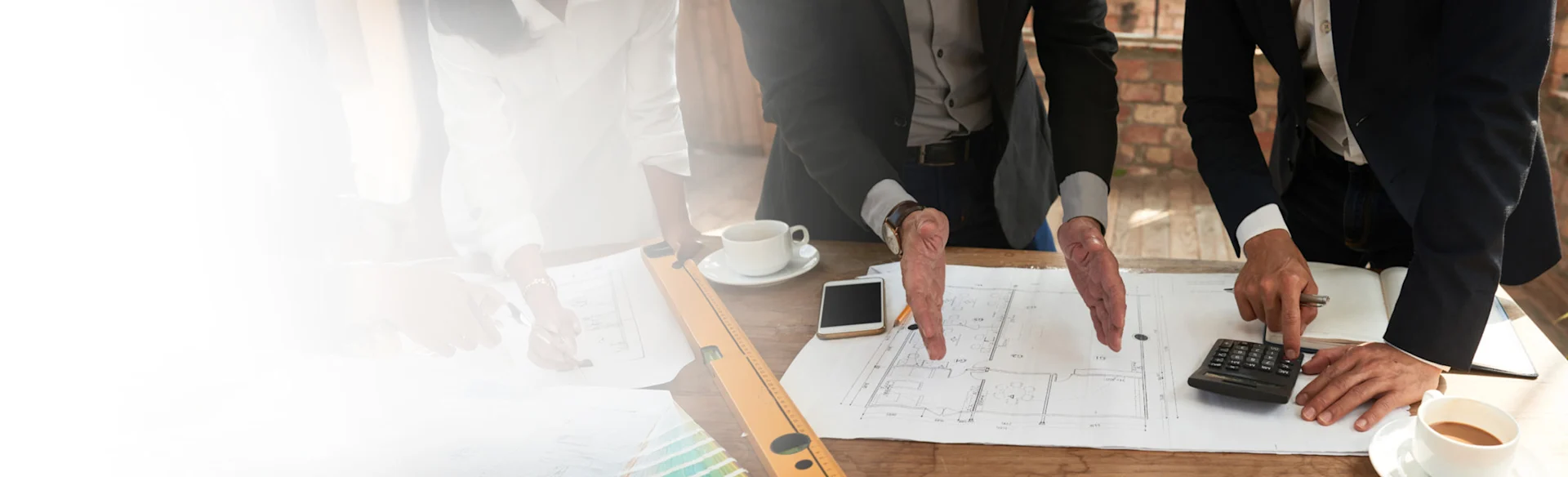Two executives looking at drawings and using a calculator 1200x801