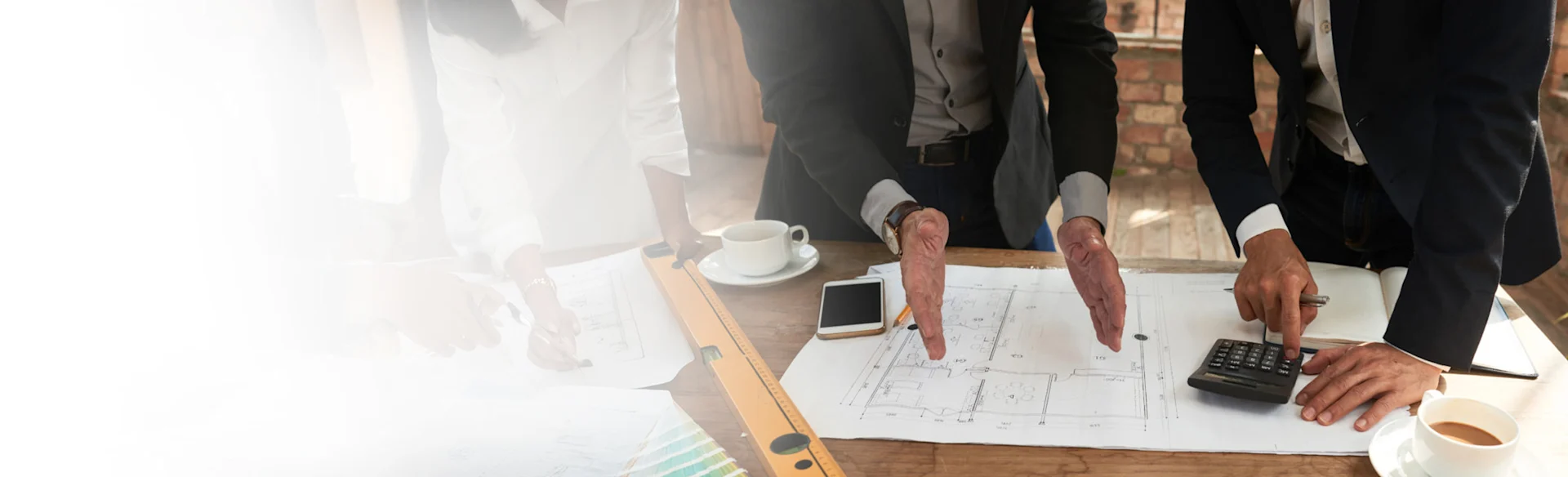 Two executives looking at drawings and using a calculator 1200x801