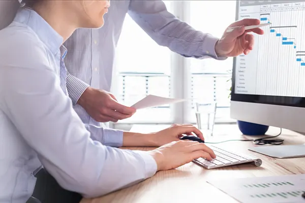 Two executives looking at project management chart on a screen THUMB