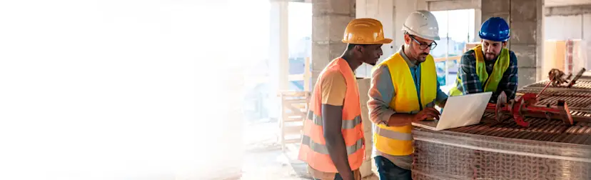 Three construction workers on site looking at an iPad - 1200x800 HERO