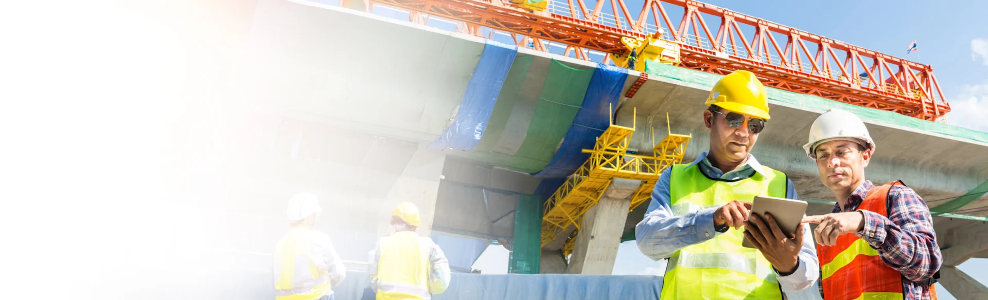 Two construction workers looking at an iPad infront of a crane 1200x800