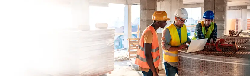 Three construction workers on site looking at an iPad 1200x800